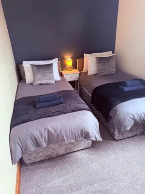 a bedroom with two beds and a table with a lamp at Eton Court Apartments in Newquay