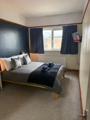 a bedroom with a large bed with blue curtains at Eton Court Apartments in Newquay