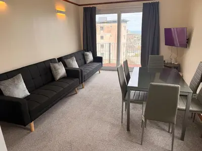 a living room with a black couch and a table at Eton Court Apartments in Newquay