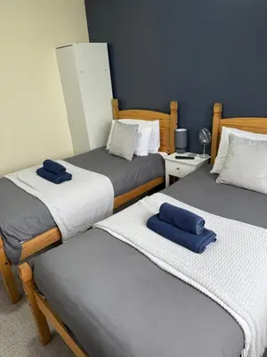 a room with three beds with blue towels on them at Eton Court Apartments in Newquay