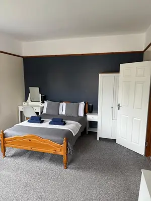 a bedroom with a large bed and a desk at Eton Court Apartments in Newquay