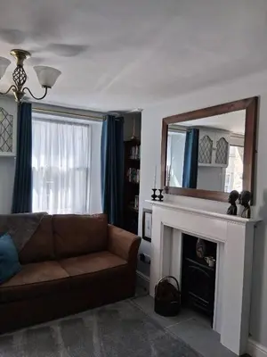 a living room with a couch and a mirror at Ivy Cottage, in Lostwithiel