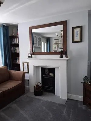 a living room with a fireplace and a mirror at Ivy Cottage, in Lostwithiel