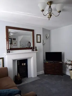 a living room with a fireplace and a mirror at Ivy Cottage, in Lostwithiel
