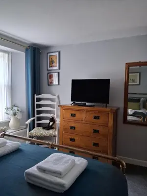 a bedroom with a tv and a dresser with a bed at Ivy Cottage, in Lostwithiel