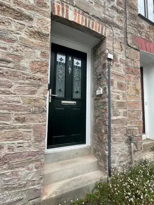 a black door on the side of a brick building at Ivy Cottage, in Lostwithiel