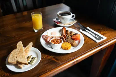 a table with two plates of breakfast food and a cup of coffee at Tyacks Hotel in Camborne