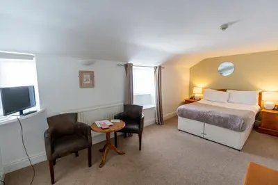 a hotel room with a bed and a table and chairs at Tyacks Hotel in Camborne