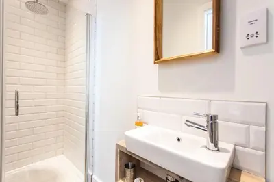 a white bathroom with a sink and a shower at Primrose House St. Ives in St Ives