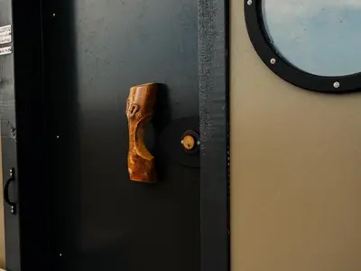 a wooden handle on a door with a mirror at YHA Treyarnon Bay in Padstow