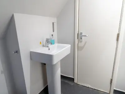 a white bathroom with a sink and a shower at YHA Treyarnon Bay in Padstow