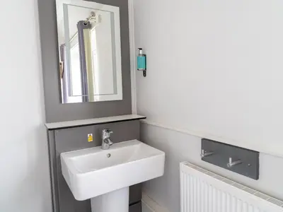 a bathroom with a white sink and a mirror at YHA Treyarnon Bay in Padstow