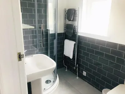 a blue tiled bathroom with a sink and a shower at Olcote House in Padstow