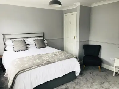 a bedroom with a bed and a blue chair at Olcote House in Padstow