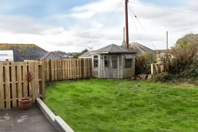a backyard with a wooden fence and a small house at Roseland House in Falmouth