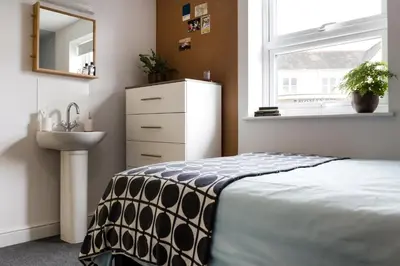 a bedroom with a bed and a sink and a mirror at Roseland House in Falmouth