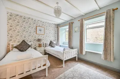 a bedroom with two beds and a window at Polean Farm Old Farmhouse - With Large Jacuzzi, Games Room, Near the Sea and with Free Access to a Nearby Pool in Looe