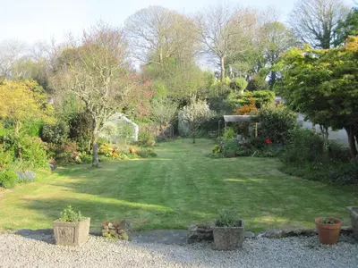 a garden with a large lawn with trees and plants at Glengarth in Penryn
