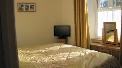 a bedroom with a bed and a tv and a window at Glengarth in Penryn