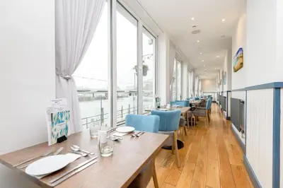 a restaurant with tables and chairs and a large window at Portbyhan Hotel in Looe