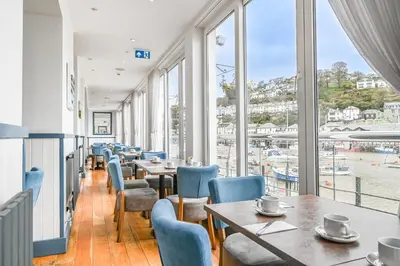 a restaurant with tables and chairs and a view of the water at Portbyhan Hotel in Looe