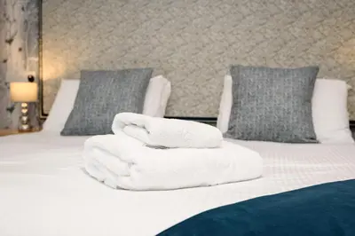 two towels are stacked on a bed with pillows at Portbyhan Hotel in Looe