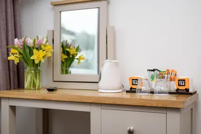 a vase of flowers on a counter with a mirror at Portbyhan Hotel in Looe