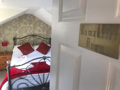 a bedroom with a bed with red pillows on it at Wellingtons in Fowey