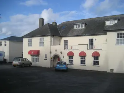 a large white building with cars parked in a parking lot at Priory Lodge Hotel in Newquay