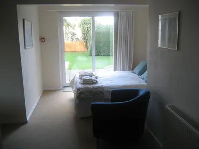 a bedroom with a bed and a chair and a window at Priory Lodge Hotel in Newquay