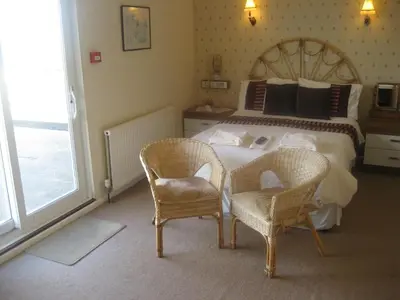 a bedroom with a large bed and two chairs at Priory Lodge Hotel in Newquay
