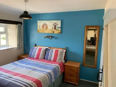 a blue bedroom with a bed and a mirror at The Hayloft in Bude