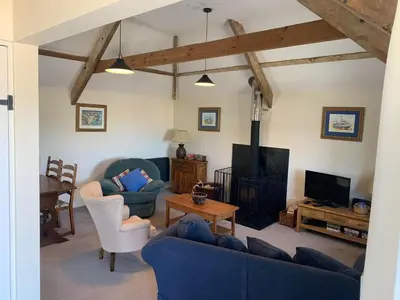 a living room with a blue couch and a tv at The Hayloft in Bude