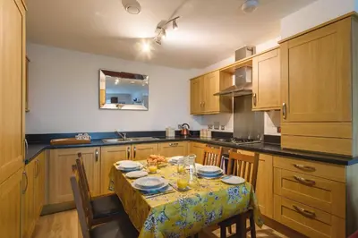 a kitchen with a table with plates and glasses on it at Panoramic Sea-View Family Appartment , Free Parking, Sleeps 6 , Walk to Beach, Station, & Town in Newquay