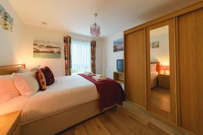 a hotel room with a bed and a television at Panoramic Sea-View Family Appartment , Free Parking, Sleeps 6 , Walk to Beach, Station, & Town in Newquay
