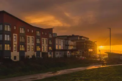 a building with the sunset in the background at Panoramic Sea-View Family Appartment , Free Parking, Sleeps 6 , Walk to Beach, Station, & Town in Newquay