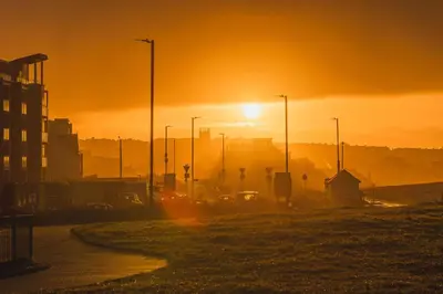 a sunset over a city with cars on a street at Panoramic Sea-View Family Appartment , Free Parking, Sleeps 6 , Walk to Beach, Station, & Town in Newquay