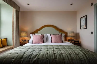 a bedroom with a large bed with pink pillows at The Wellington Hotel in Boscastle