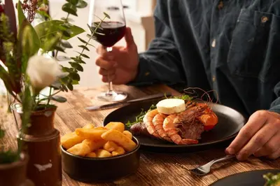 a man holding a glass of wine and a plate of food at The Wellington Hotel in Boscastle