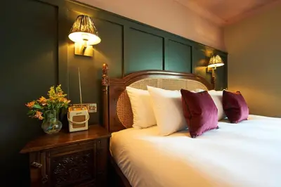 a bedroom with a bed with white sheets and purple pillows at The Wellington Hotel in Boscastle