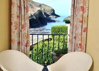a room with a balcony with a view of the ocean at Port Gaverne Hotel in Port Isaac