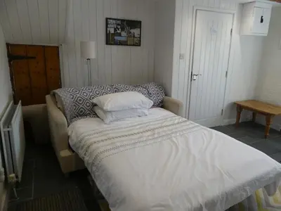 a bed in a bedroom with a white comforter at Priory Cottage Bodmin in Bodmin