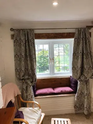 a window seat with a pink pillow in a room at Priory Cottage Bodmin in Bodmin