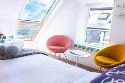 a bedroom with two chairs and a bed and two windows at No4 St Ives in St Ives