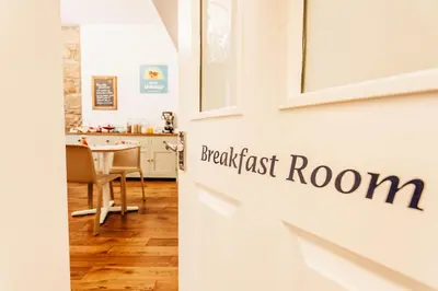 a kitchen and dining room with a white door with the words breakfast first room at No4 St Ives in St Ives