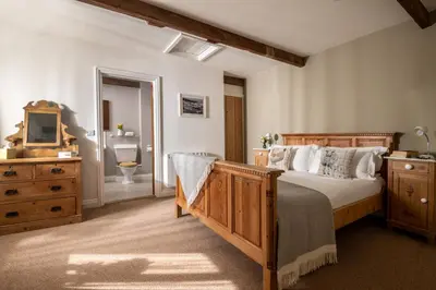 a bedroom with a large bed and a bathroom at Lambriggan Court in Perranzabuloe