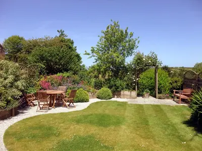 a garden with a table and chairs and a lawn at Lambriggan Court in Perranzabuloe