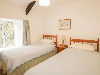 two beds in a room with a window at Miller's House in Tintagel