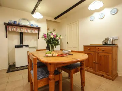 a kitchen with a wooden table with flowers on it at Miller's House in Tintagel