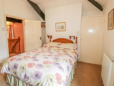 a bedroom with a bed with a floral bedspread at Miller's House in Tintagel